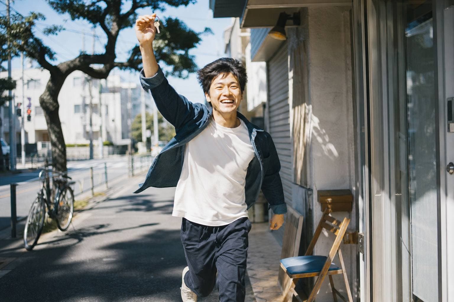 店舗の鍵を持って、朝の光の中を走り出す若者